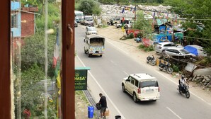A road with vehicles and a person standing by the roadside. - Hotel Ayaan Residency Manali  (Manali)