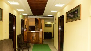A reception area with a reception desk, a green carpet, and a staircase leading to an upper floor. - Hotel Ayaan Residency Manali  (Manali)