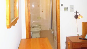 Une pièce comprenant une table en bois, une chaise en bois, des toilettes et un miroir.