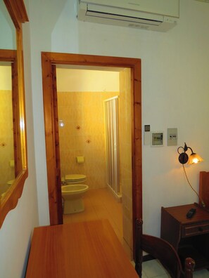 A bathroom with a toilet, shower, and a wooden door leading to another room. - second floor double bedroom (Lipari)