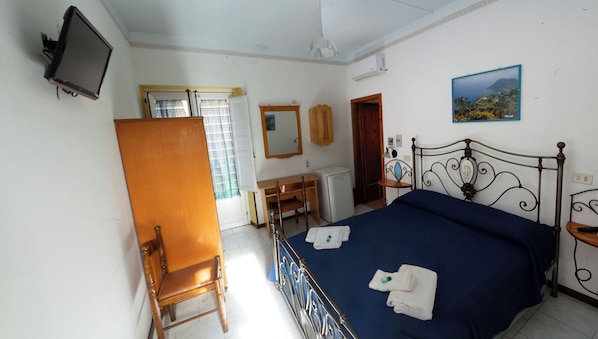 A bedroom with a bed, a desk, a chair, a television, and a painting on the wall. - second floor double bedroom (Lipari)