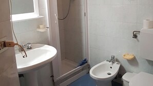 Une salle de bain équipée d’un lavabo, d’un bidet, de toilettes et d’une douche.
