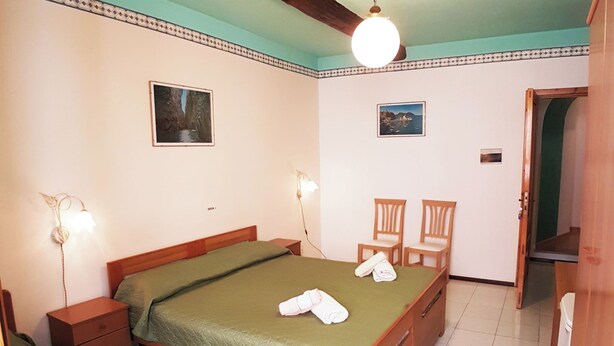 Une chambre à coucher comprenant un lit, deux tables de chevet, une chaise et une armoire.