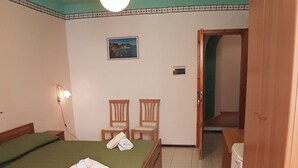 Une chambre avec deux lits, une armoire en bois, une petite table et une chaise.