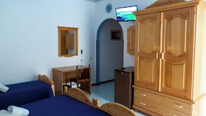 Un dormitorio con dos camas, un armario de madera, un escritorio y una televisión.