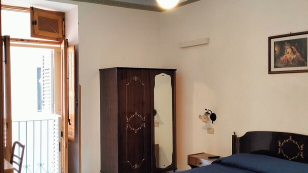 A bedroom with a bed, a wardrobe, a ceiling fan, a painting, and a balcony. - single room with ceiling fan (Lipari)