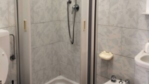 A bathroom with a glass-enclosed shower, a toilet, and a bidet. - single room with ceiling fan (Lipari)