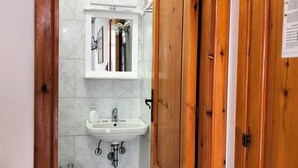 A bathroom with a wooden door, a sink, a bidet, and a mirror. - single room with ceiling fan (Lipari)