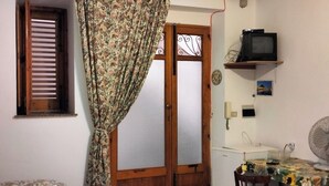 A room with a bed, a desk with a computer, a chair, a ceiling fan, and a window with curtains. - economy central chamber (Lipari)