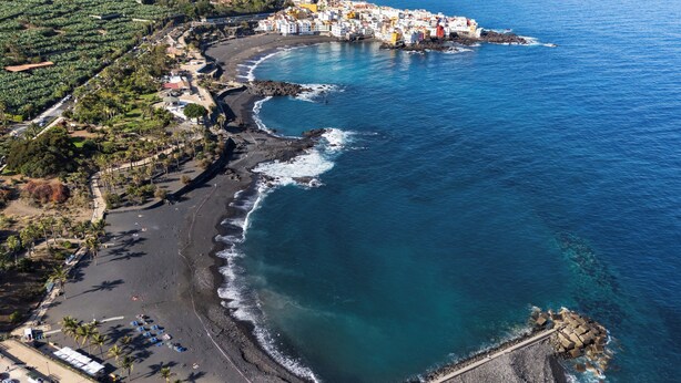 Vue aérienne d’une ville côtière avec une plage, une côte rocheuse et des bâtiments le long de la côte.