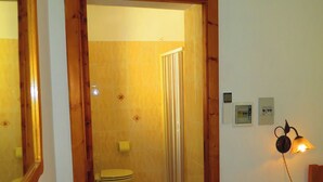 Une salle de bain avec des toilettes, une douche et un cadre de porte en bois.