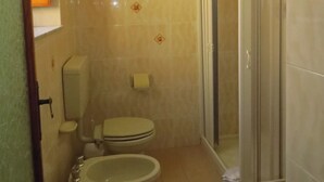 Une salle de bain équipée de toilettes, d’un bidet et d’une douche à parois de verre.