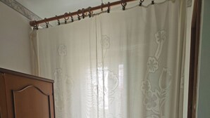A room with a wooden wardrobe, a floral curtain, and a tiled floor.