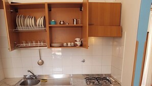 A compact kitchen with wooden cabinets, a sink, and a gas stove.