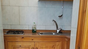 Une petite cuisine avec des meubles en bois, un évier en acier inoxydable et une cuisinière à gaz.