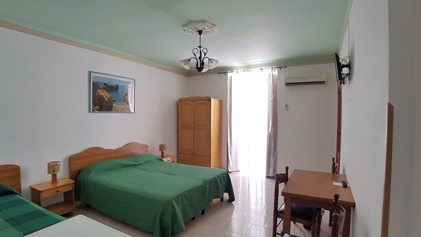 Une chambre à coucher comprenant un lit, un bureau, une armoire et un ventilateur de plafond.