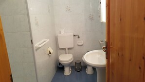 Une petite salle de bain avec des toilettes, un lavabo et une poubelle.