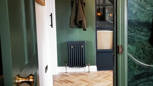 A hallway with a herringbone floor, a radiator, and a coat hanging on the wall. - Architect designed home in the heart of Stow-on-the-Wold (Stow on the Wold)