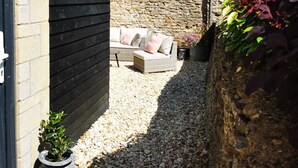 A narrow outdoor space with a stone wall, a wooden bench, and a small table. - Architect designed home in the heart of Stow-on-the-Wold (Stow on the Wold)