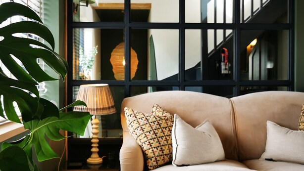 A living room with a beige sofa, a wooden coffee table, and a large green plant. - Architect designed home in the heart of Stow-on-the-Wold (Stow on the Wold)