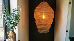A hallway with a hanging woven light fixture, a potted plant, and a clear glass vase with reed sticks. - Architect designed home in the heart of Stow-on-the-Wold (Stow on the Wold)