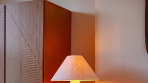 Une chambre moderne avec un lampadaire au design original, une armoire en bois et un meuble rouge.