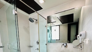 A modern bathroom with a glass-enclosed shower, a white sink, and a large mirror. - Qotel Signature Lavish Inn Rajouri Garden (New Delhi)