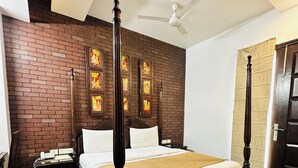 A four-poster bed in a room with a brick wall and a ceiling fan. - Qotel Signature Lavish Inn Rajouri Garden (New Delhi)
