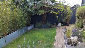 A garden with a grassy area, lavender plants, a brick pathway, and various potted plants. - 1-bed Apartment - Sleeps 2 & Private Parking (Llansantffraid-ym-Mechain)