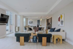A modern living room with a sofa set, a coffee table, and a TV mounted on the wall.