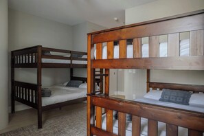 A room with two bunk beds, a wooden headboard, and a carpeted floor.