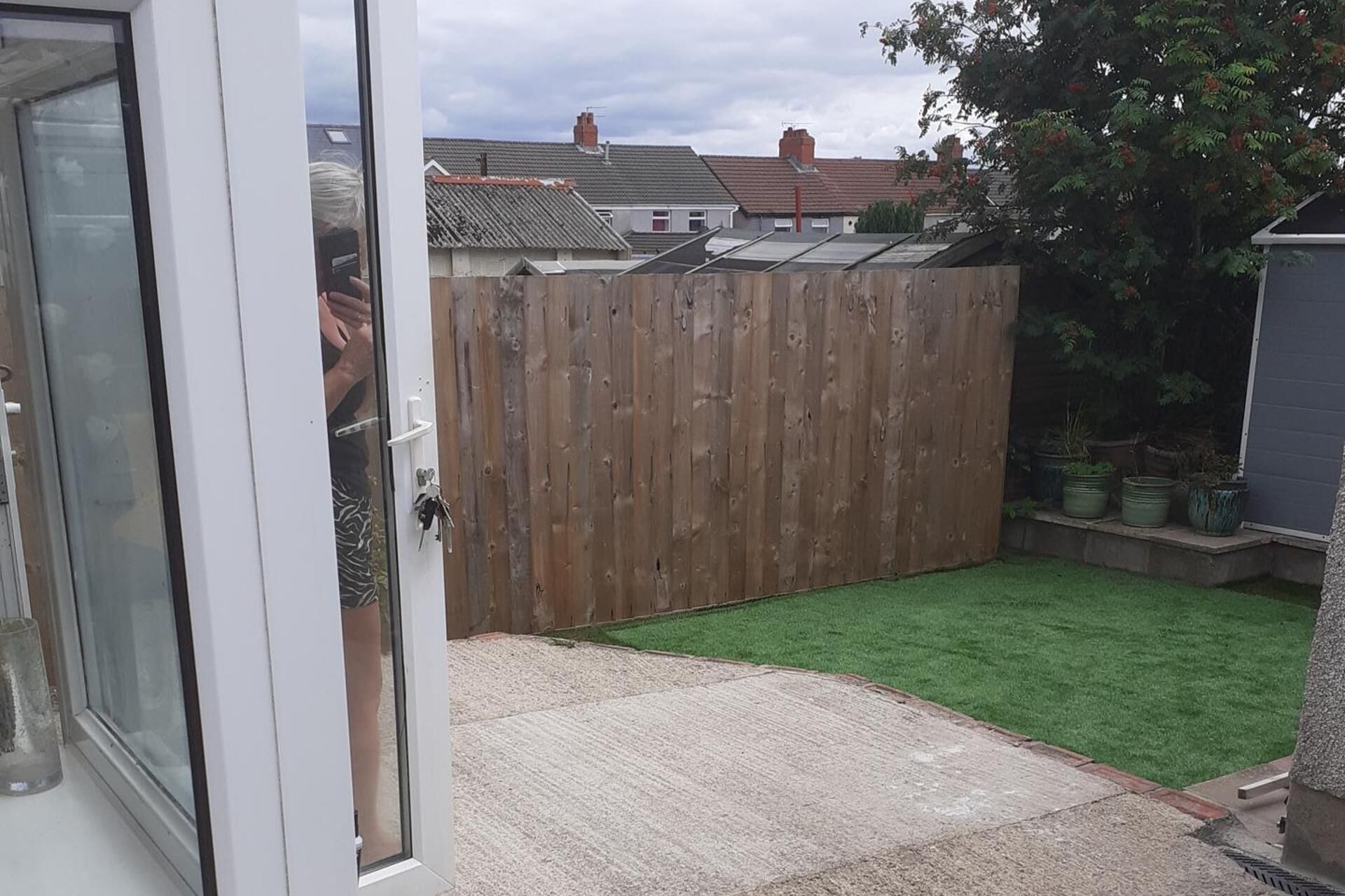 A fenced backyard with artificial grass and a wooden fence.