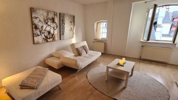 A modern living room with a sofa, a smaller couch, a coffee table, and a lamp.