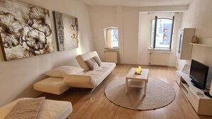 A modern living room with a sofa, a coffee table, a TV, and artwork on the walls.