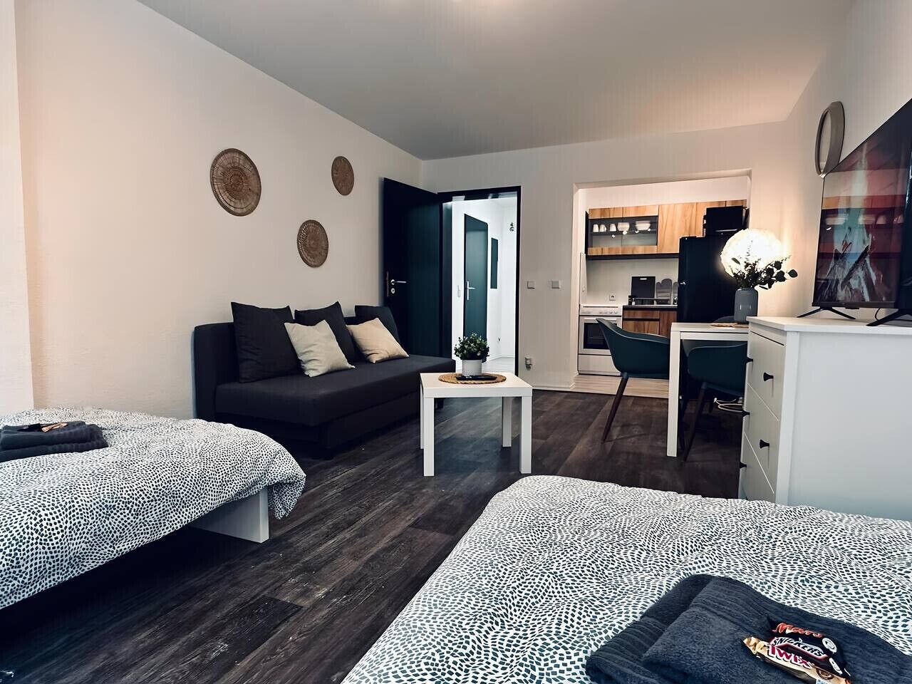 A modern living room with a sofa, a coffee table, and a dining area with a desk and chairs.