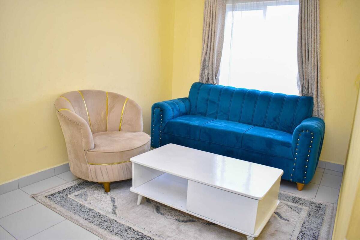 Una sala de estar con un sillón color beige, un sofá azul y una mesa de centro blanca.