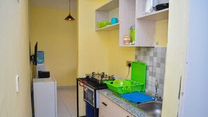 Una cocina compacta con refrigerador, lavamanos y una pequeña encimera.