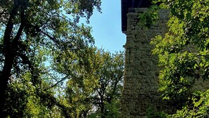 Ein Steinhaus mit einer hölzernen Brücke, umgeben von viel Grün.