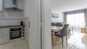 Una cocina moderna con armarios blancos, una campana extractora de acero inoxidable y un horno empotrado.