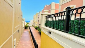 A narrow, paved pathway flanked by buildings with balconies and a decorative fence. - Enjoy 1 BR Palm Mar Next to Pool (Arona)