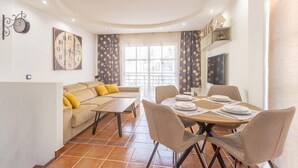 A dining area with a round table, chairs, and a sofa with yellow cushions. - Aqua Vista 2 bed Penthouse With Great Views (Adeje)