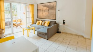 A modern living room with a grey sofa, yellow cushions, a white coffee table, and a large painting on the wall.