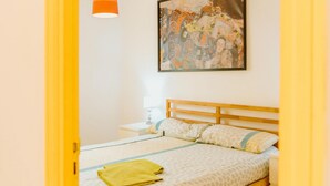 A bedroom with a bed, a nightstand, a lamp, and a painting on the wall.