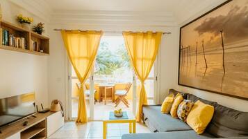Relax in this stylish living room with a sofa, coffee table, and flat-screen TV, plus a balcony with a table and chairs.