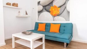A modern living room with a teal sofa, white coffee table, and a painting of stones and a flower. - Central 2bedroom 200m From Beach (Adeje)