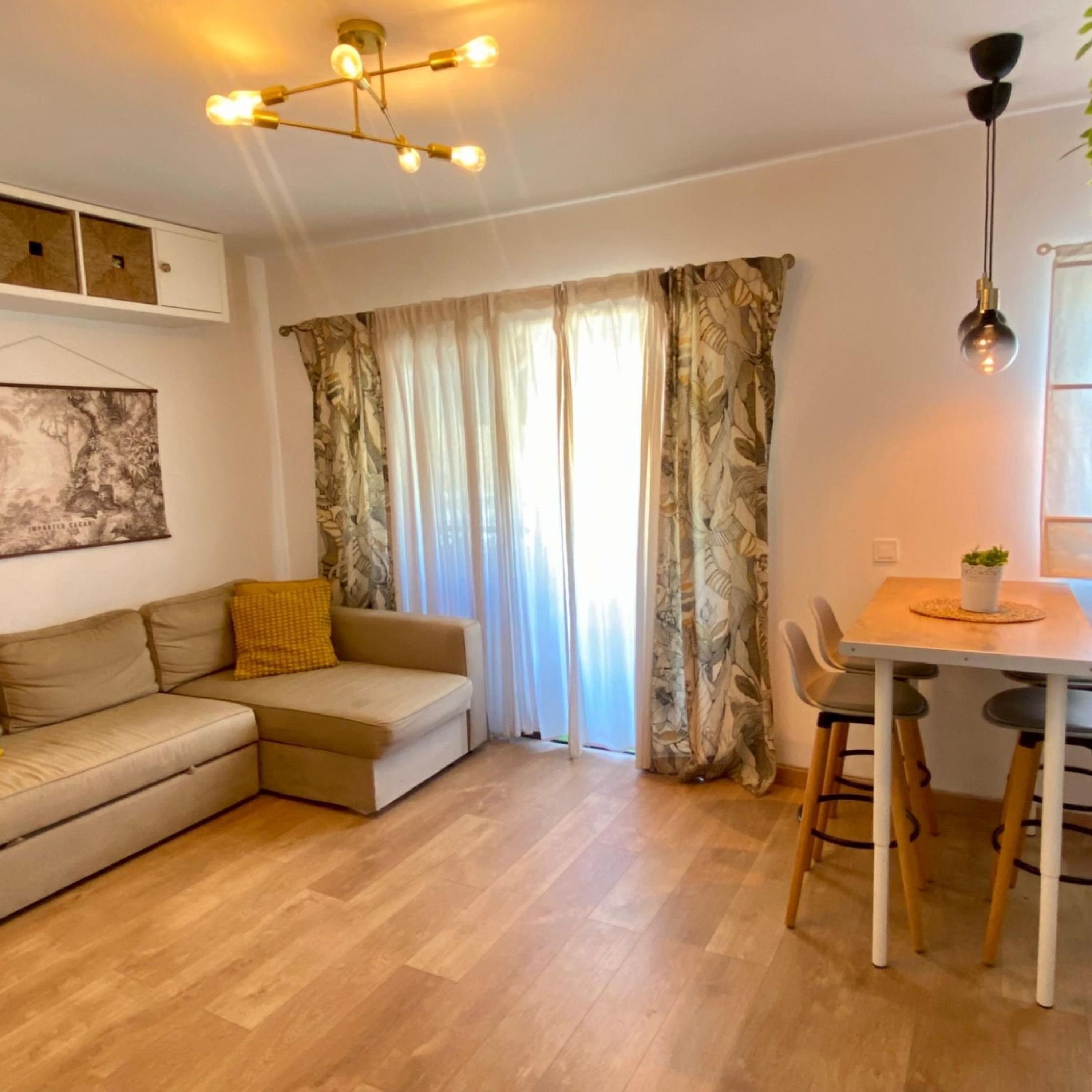 Un salon moderne avec un canapé, un coin repas comprenant une table et des chaises, et un luminaire fixé au plafond.