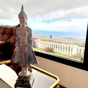 Una estatua sobre una mesa, con vistas a un paisaje urbano a través de una ventana.
