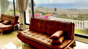 A room with a large window, a leather sofa, and a chair. - Villa in La Orotava 7 Bedrooms 1 bed 7 Baths (La Orotava)