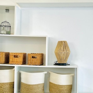 A white shelf with wicker baskets and a woven lamp.