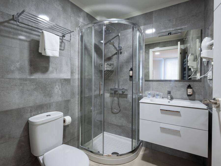 A modern bathroom with a glass-enclosed shower, a toilet, a sink with a mirror, and a towel rack.